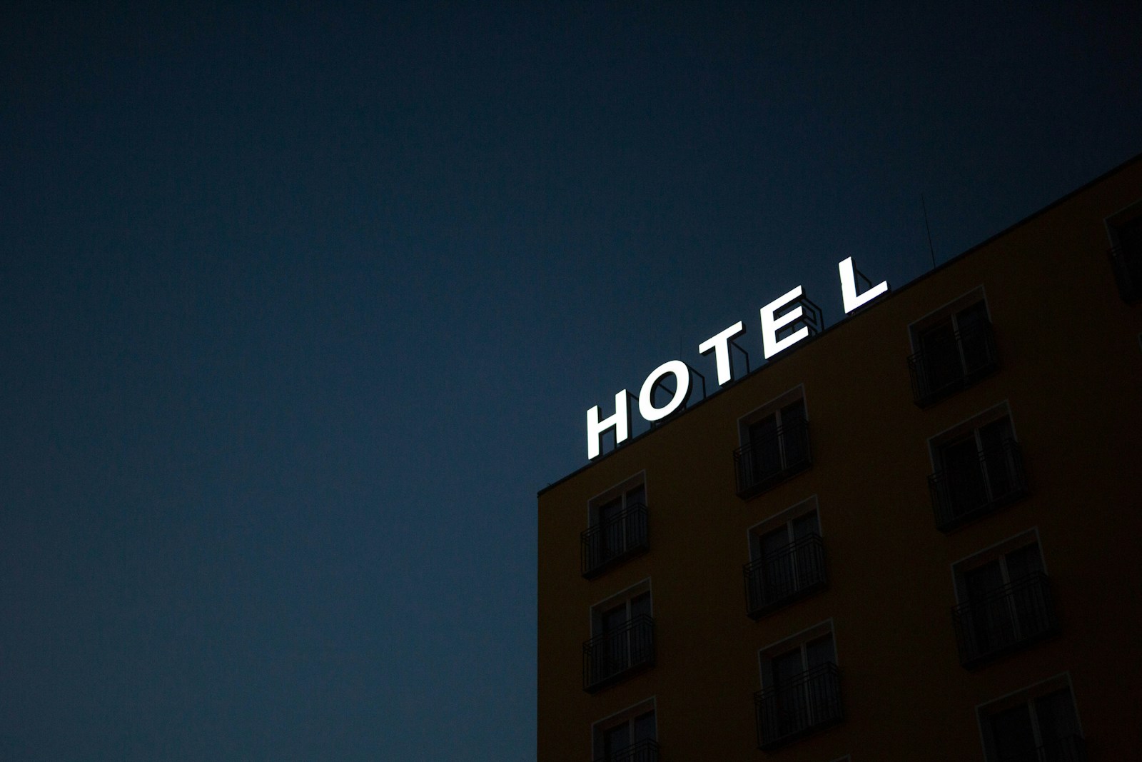 photo en contre-plongée de la signalisation lumineuse de l'hôtel au sommet d'un bâtiment marron pendant la nuit