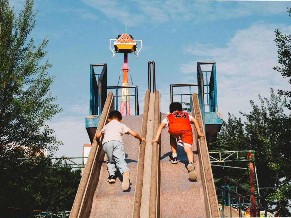 Deux enfants glissent sur une glissière en bois dans un parc de loisirs