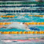 Nageur en action dans une piscine, bras tendu, eau en mouvement, lignes de séparation
