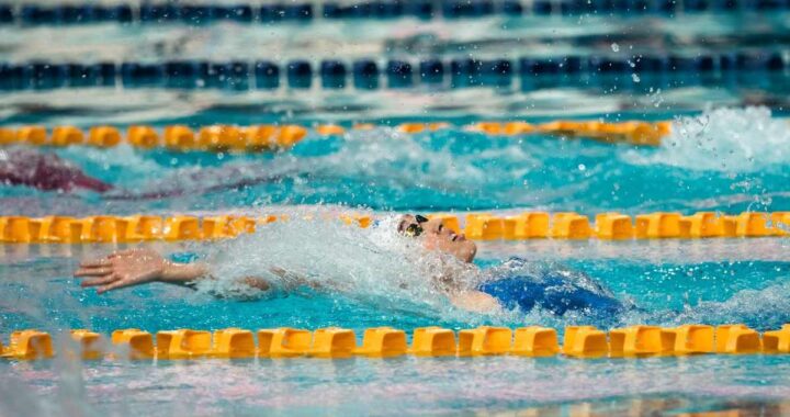 Nageur en action dans une piscine, bras tendu, eau en mouvement, lignes de séparation