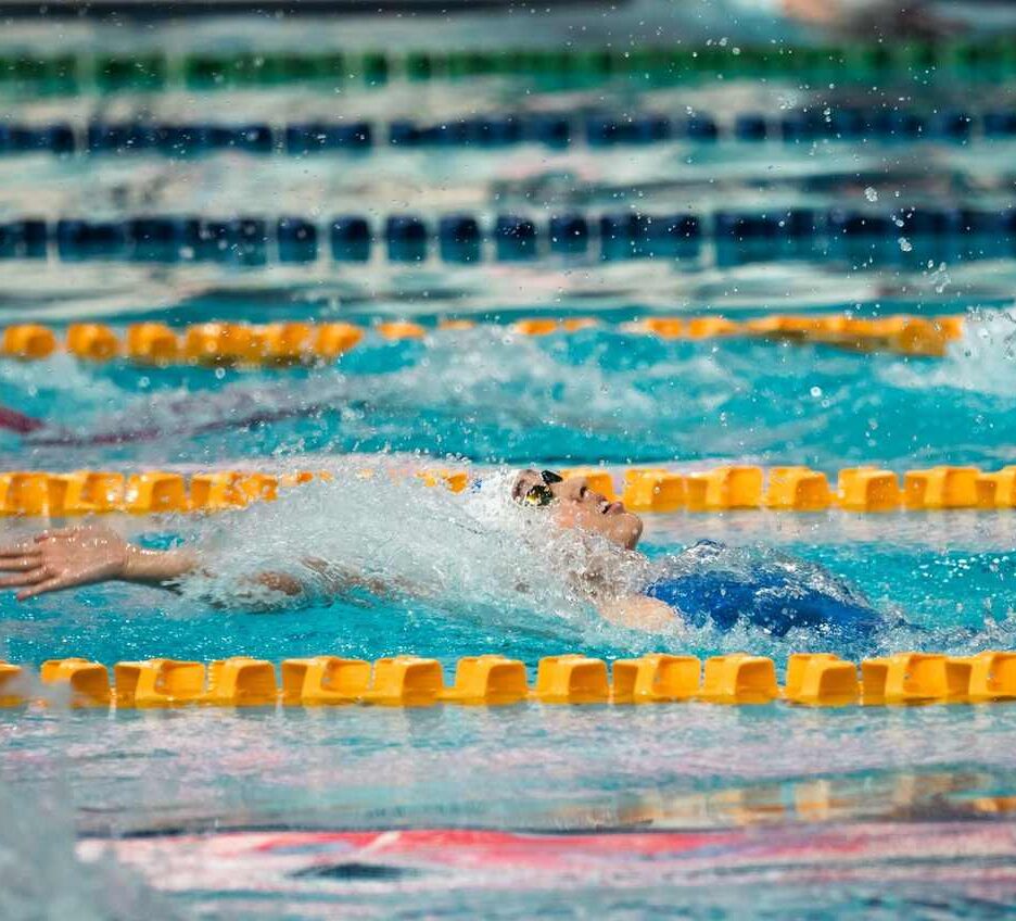 Nageur en action dans une piscine, bras tendu, eau en mouvement, lignes de séparation