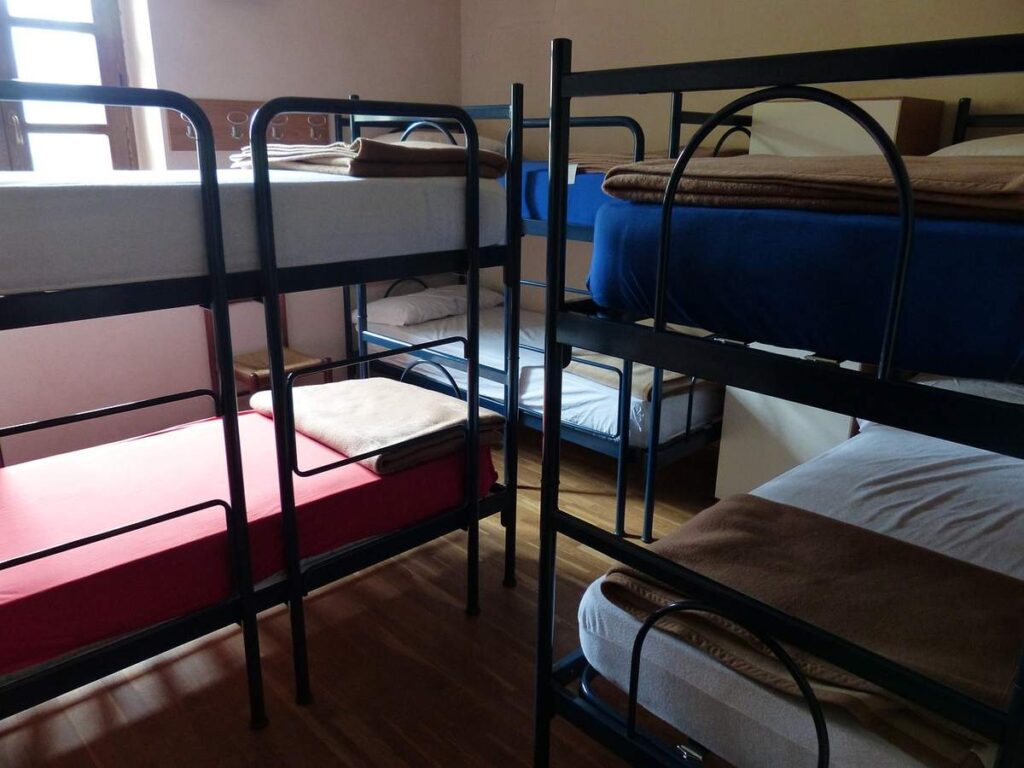 Salle de dortoir avec plusieurs lits superposés et matelas variés