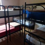 Salle de dortoir avec plusieurs lits superposés et matelas variés