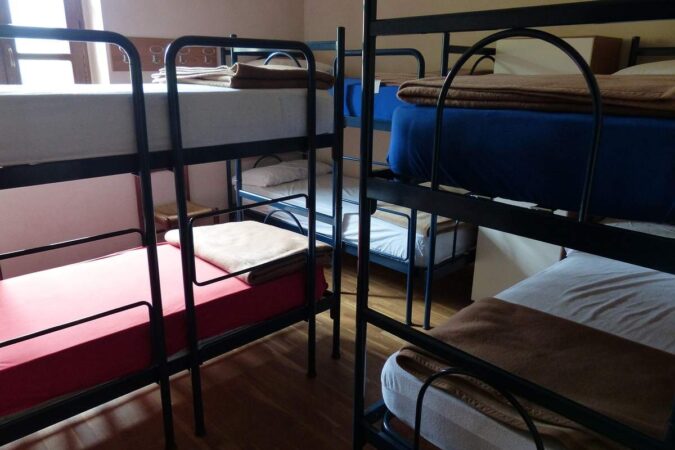 Salle de dortoir avec plusieurs lits superposés et matelas variés