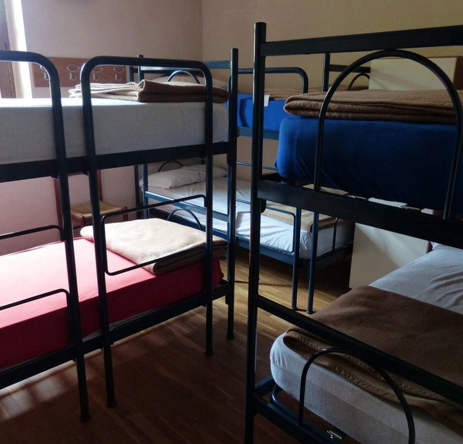 Salle de dortoir avec plusieurs lits superposés et matelas variés