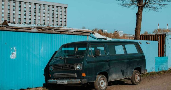 Van noir à côté d'un conteneur bleu sous un ciel clair