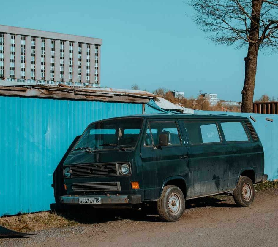 Van noir à côté d'un conteneur bleu sous un ciel clair