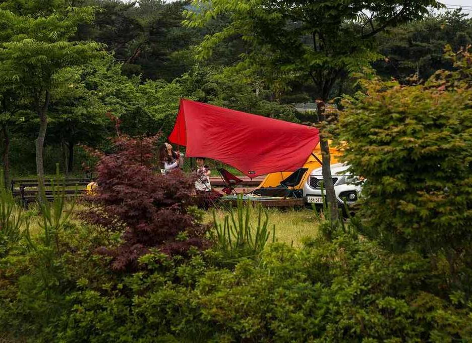 Voile rouge drapé sur un camping-car, entouré de verdure et d'arbres