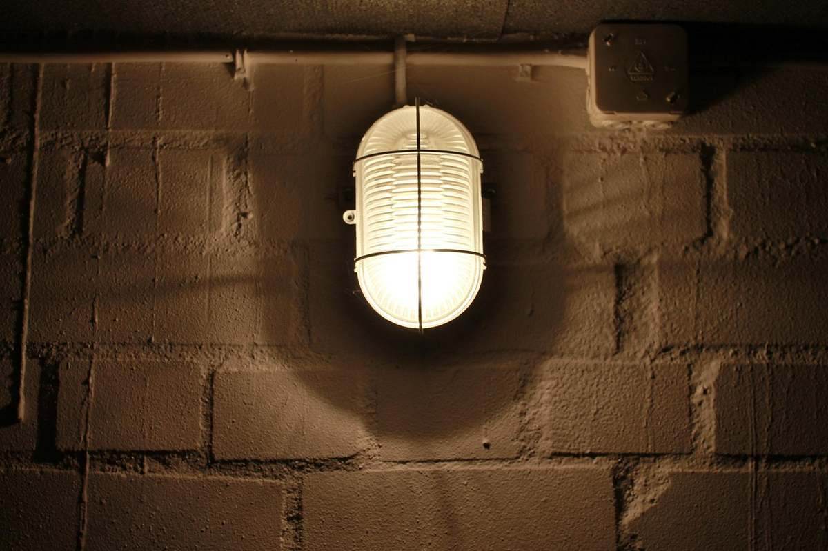 Lampe cylindrique blanche fixée à un mur en briques, lumière forte Lampe cylindrique blanche fixée à un mur en briques, lumière forte