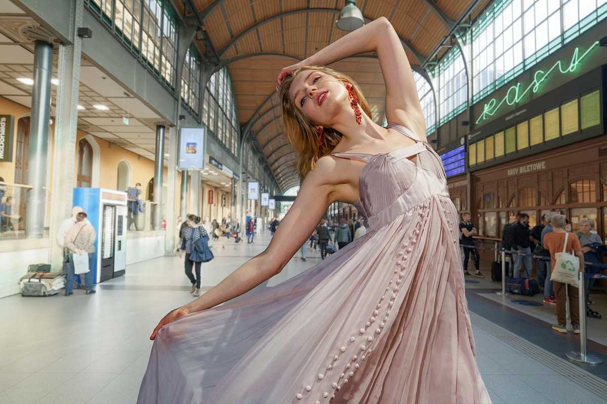 Une femme en robe fluide pose élégamment dans une grande gare Une femme en robe fluide pose élégamment dans une grande gare