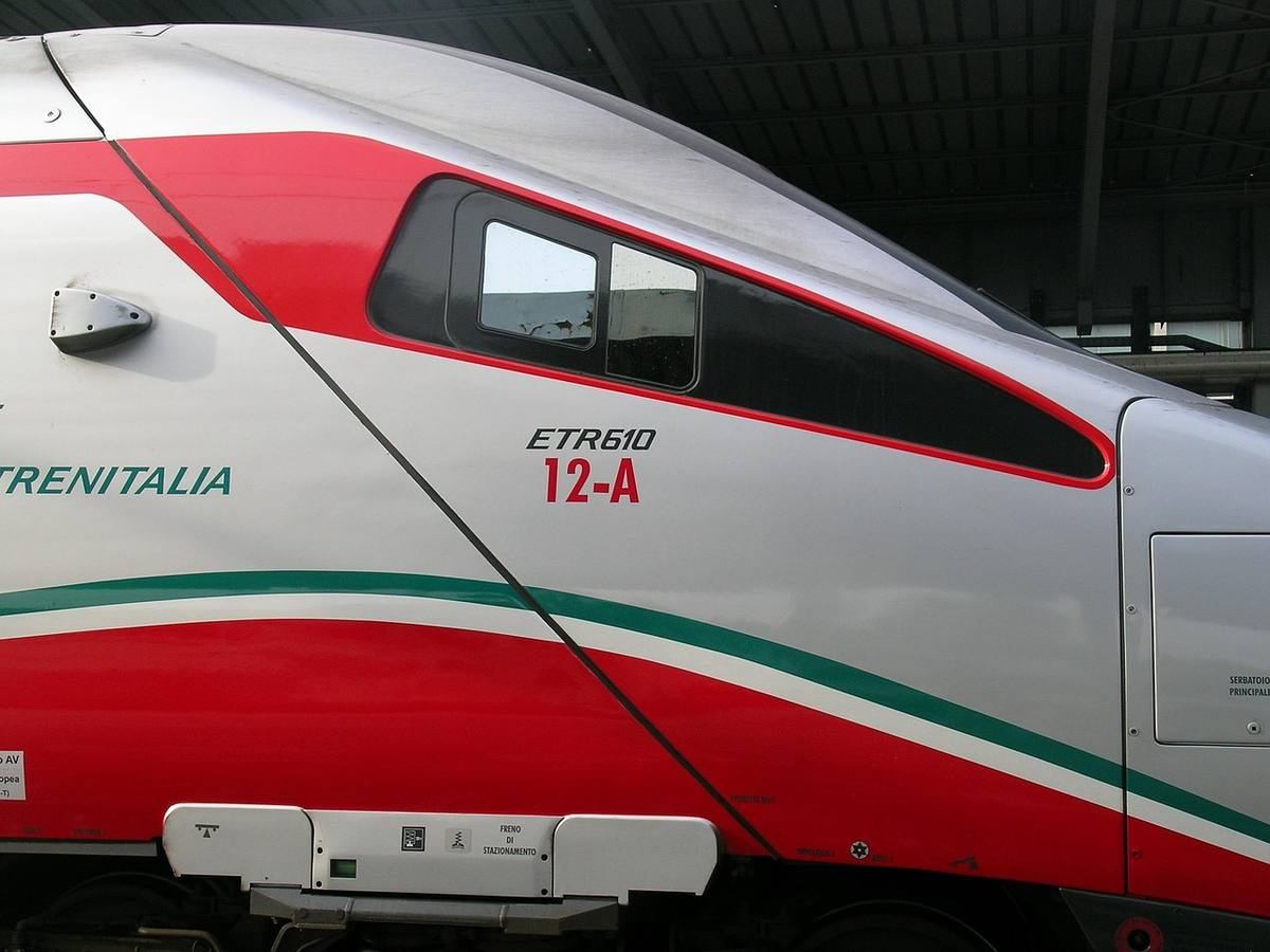 Train de voyageurs Trenitalia ETR610 blanc et rouge stationné sous abri ferroviaire Train de voyageurs Trenitalia ETR610 blanc et rouge stationné sous abri ferroviaire