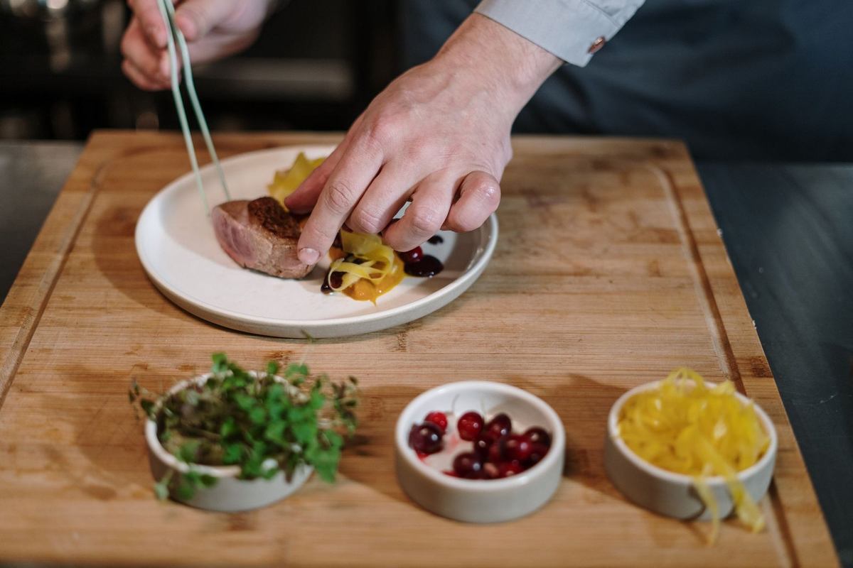 Une assiette de viande avec des herbes, des baies et des zestes de citron sur une planche à découper Une assiette de viande avec des herbes, des baies et des zestes de citron sur une planche à découper