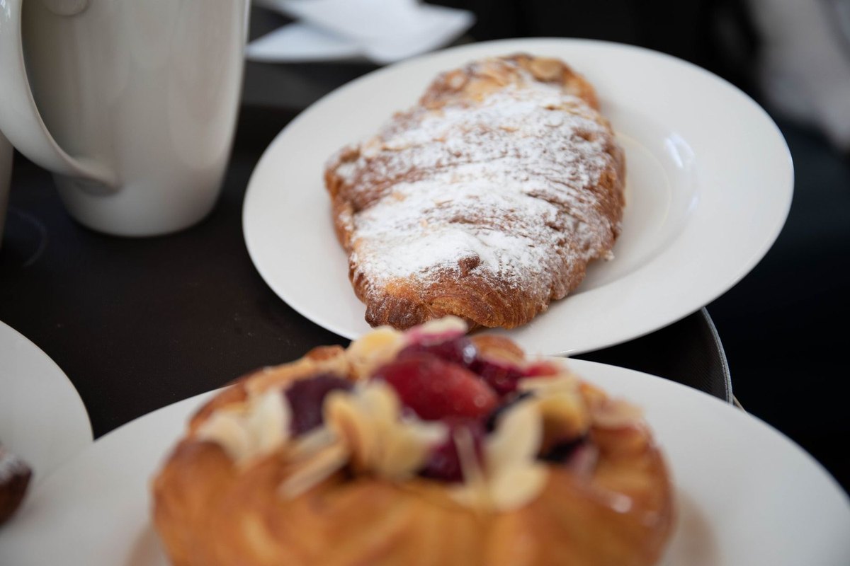 Croissant fariné et pâtisserie garnie sur assiette blanche Croissant fariné et pâtisserie garnie sur assiette blanche