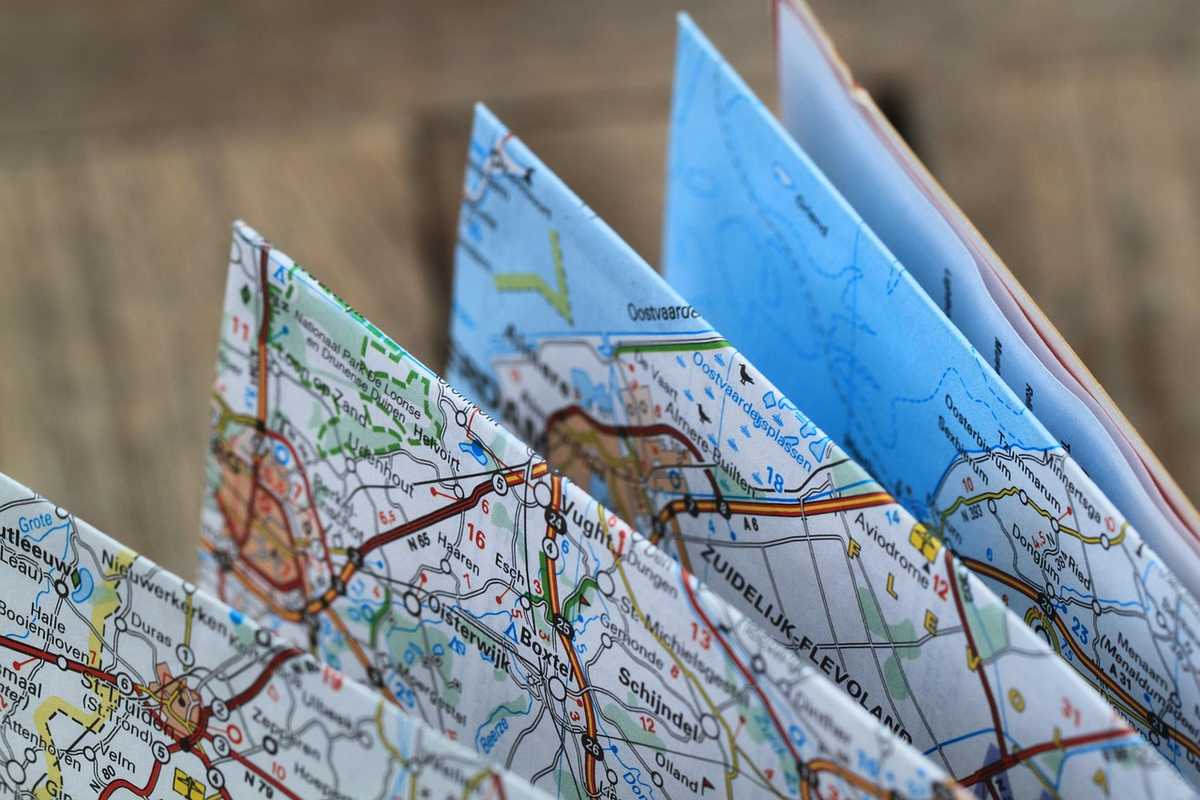 Cartes pliées en éventail, plans détaillés, main les tient Cartes pliées en éventail, plans détaillés, main les tient