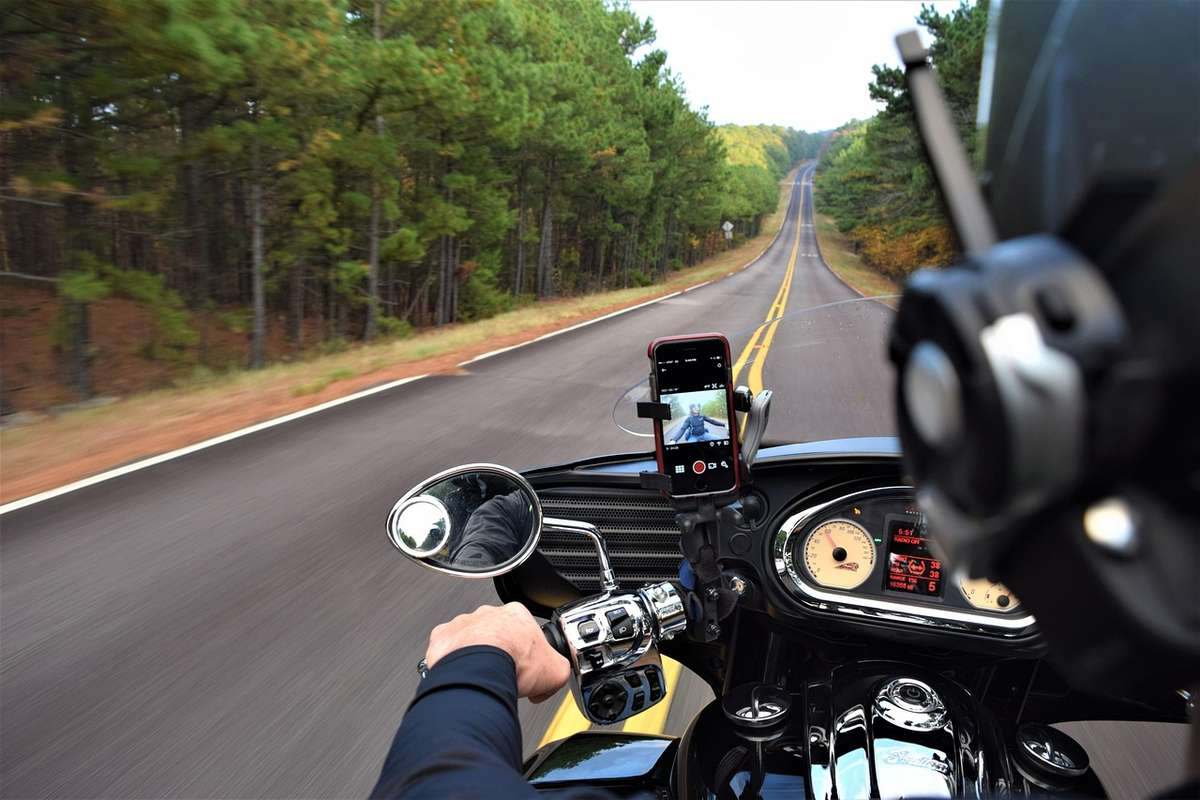 Point de vue du motard roulant sur une autoroute rectiligne bordée de forêts