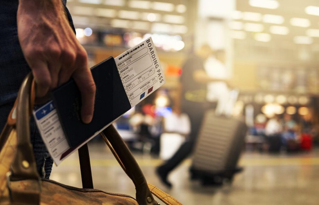 Main tenant passeport et carte d'embarquement à l'aéroport. Voyageur avec valises. Activité de voyage