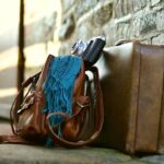 Sac valise appareil photo écharpe posés contre mur de pierre