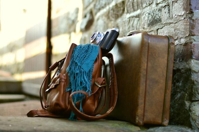 Sac valise appareil photo écharpe posés contre mur de pierre