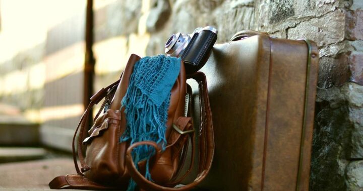 Sac valise appareil photo écharpe posés contre mur de pierre