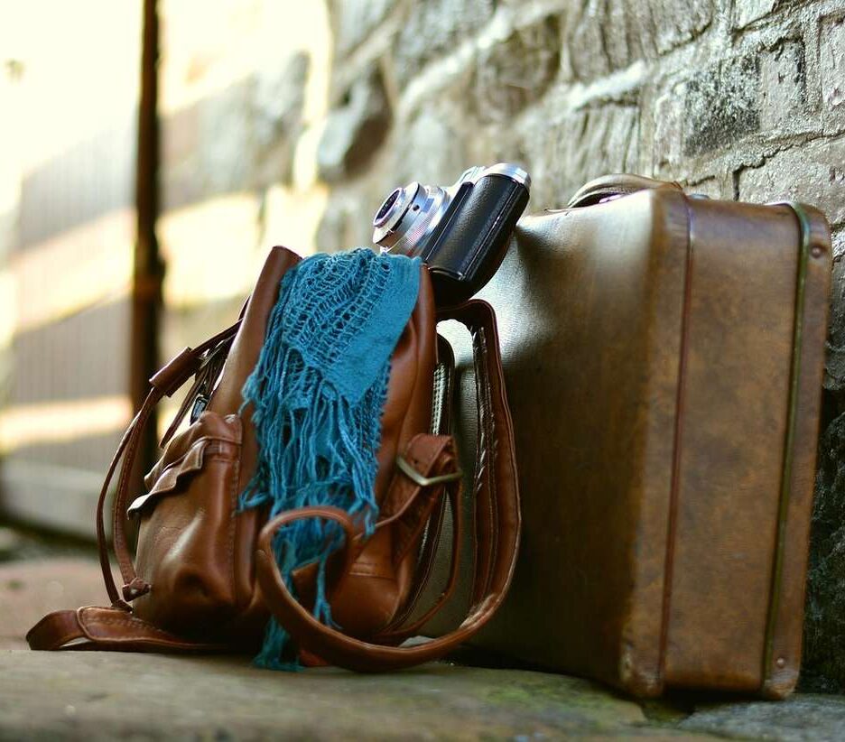 Sac valise appareil photo écharpe posés contre mur de pierre