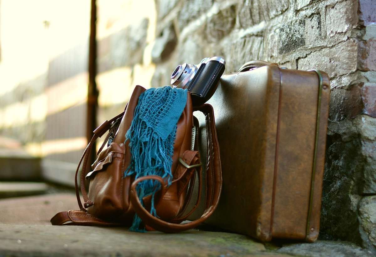 Sac valise appareil photo écharpe posés contre mur de pierre