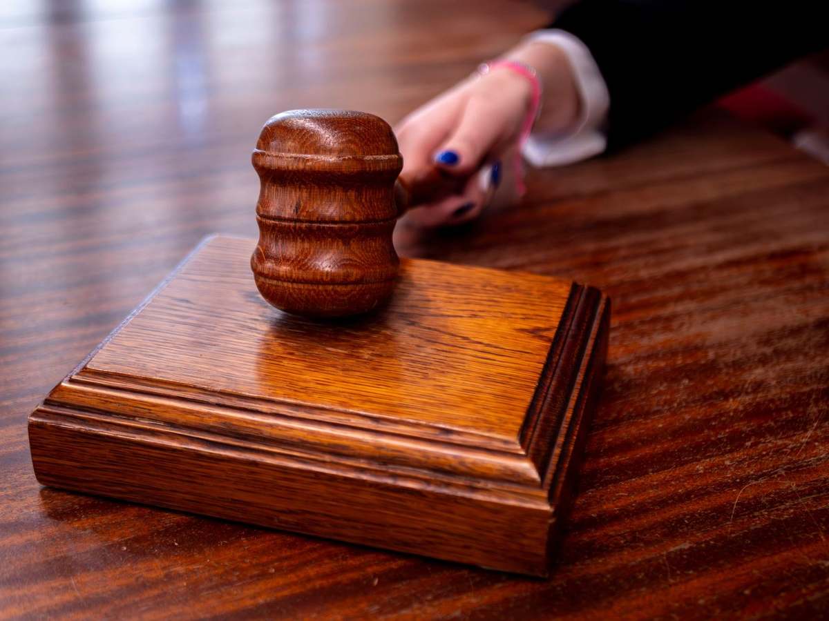 Gavel posé sur un bloc de bois, main avec vernis bleu en contact Gavel posé sur un bloc de bois, main avec vernis bleu en contact