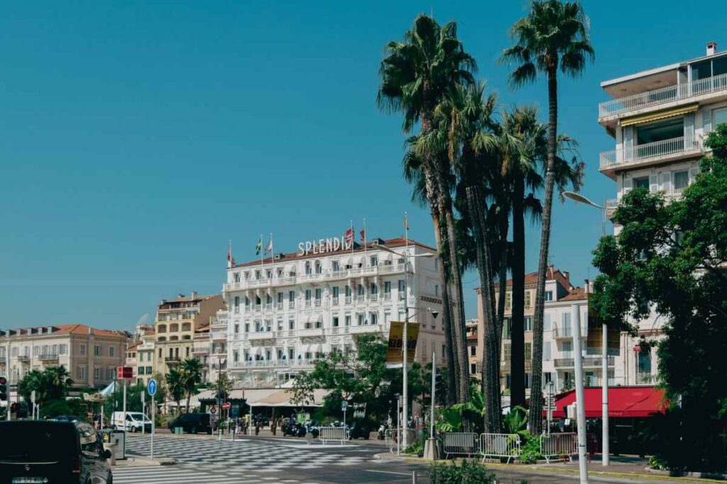 Une rue animée avec des palmiers, un grand hôtel et des voitures