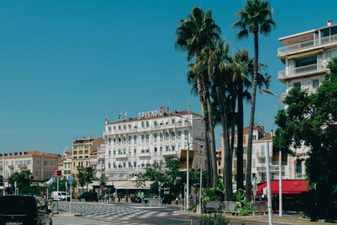 Une rue animée avec des palmiers, un grand hôtel et des voitures