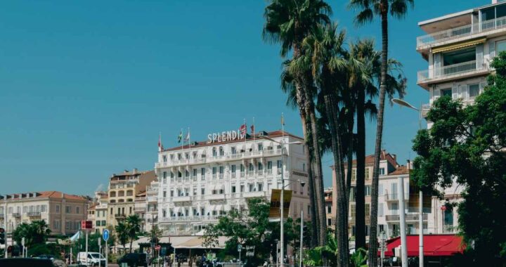 Une rue animée avec des palmiers, un grand hôtel et des voitures